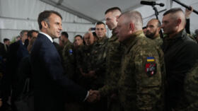 France's President Emmanuel Macron (L) shakes hands with Ukrainian soldiers during a visit in a military camp, for the first time since France has trained Ukrainian troops for the country's fight agai