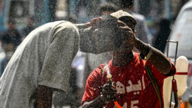 A volunteer sprays water on a passerby's head to help them cool off amid a heatwave in Karachi on April 21, 2025.