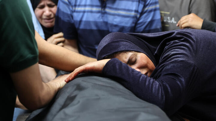 A Palestinian woman mourns over the body of a man in the morgue of the Al-Shifa hospital, following an Israeli strike that hit Gaza City's Thai restaurant on May 7, 2025.