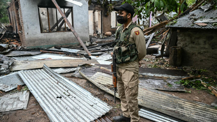 A security personnel stands next to a house destroyed by Pakistani artillery shelling at the Salamabad village in Uri, about 110kms from Srinagar, on May 8, 2025.