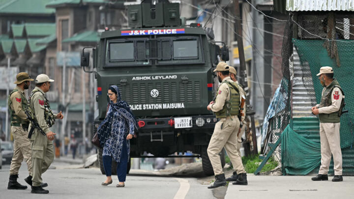 Indian policemen stand guard as a woman walks along a street in Srinagar on May 9, 2025.
