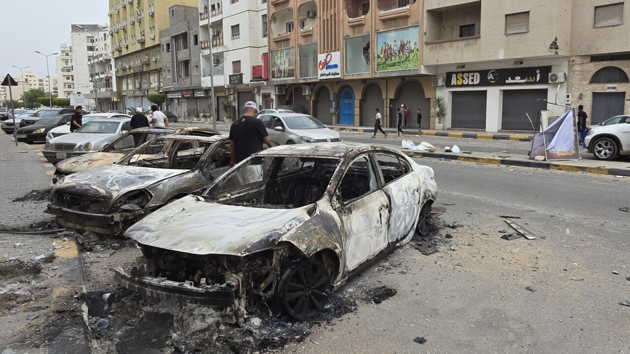 Burnt cars line a street in Tripoli on May 14, 2025, following renewed clashes in Libya's capital.