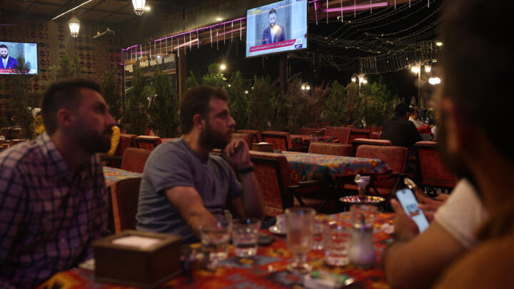 Syrians watch a televised speech by Syria's leader Ahmed al-Sharaa at a cafe in Aleppo on May 14, 2025.