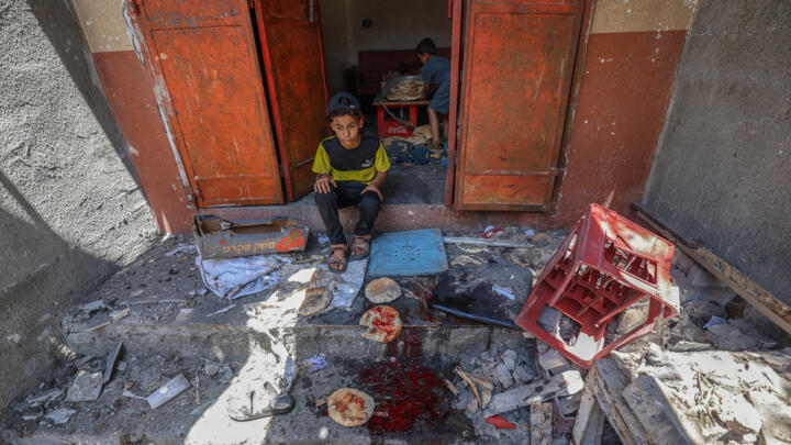 Palestinian boys salvage bread from a makeshift bakery hit in Israeli strikes at the Nuseirat refugee camp in the central Gaza Strip on May 8, 2025.