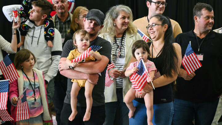 The first group of white Afrikaners to arrive in the United States for resettlement pose for photographers at Dulles Airport in Virginia