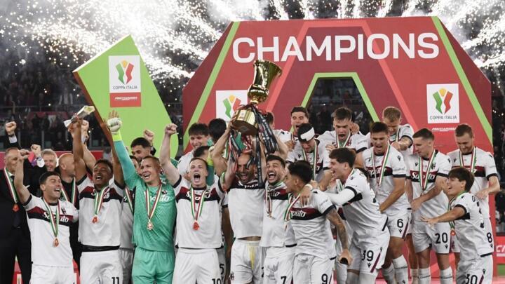 مدافع بولونيا لورنزو دي سيلفستري والمهاجم ريكاردو أورسوليني وهما يرفعان كأس إيطاليا عاليا احتفالا بالتتويج التاريخي بعد الفوز على ميلان في النهائي الذي أُقيم في الملعب الأولمبي بروما مساء 14 أيار/مايو 2025.