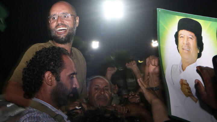 Muammar Gaddafi's son Saif al-Islam (top left) gestures to troops loyal to his father in Tripoli in August 2011, months before the late dictator's fall.