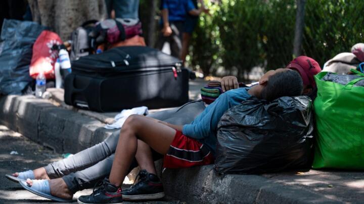 Un par de migrantes de diferentes nacionalidades permanecen afuera de un albergue municipal mientras esperan pasar la noche en la Ciudad de México el 6 de junio de 2024. Cientos de ciudadanos migrantes de Venezuela, Perú y países centroamericanos permanecen varados en la Ciudad de México, a la espera de una cita por parte de la Comisión Mexicana de Ayuda a Refugiados para la extensión de un documento que les permita llegar a la frontera entre México y Estados Unidos en busca de asilo.