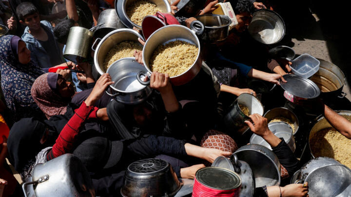 Palestinians gather as they receive food cooked by a charity kitchen, in Khan Younis, southern Gaza Strip, April 29, 2025.