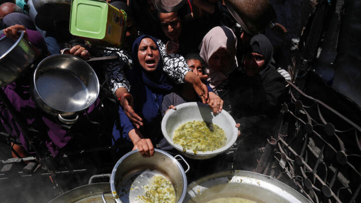 Palestinos reciben alimentos cocinados por una cocina benéfica, en Beit Lahia, norte de la Franja de Gaza, 8 de mayo de 2025.