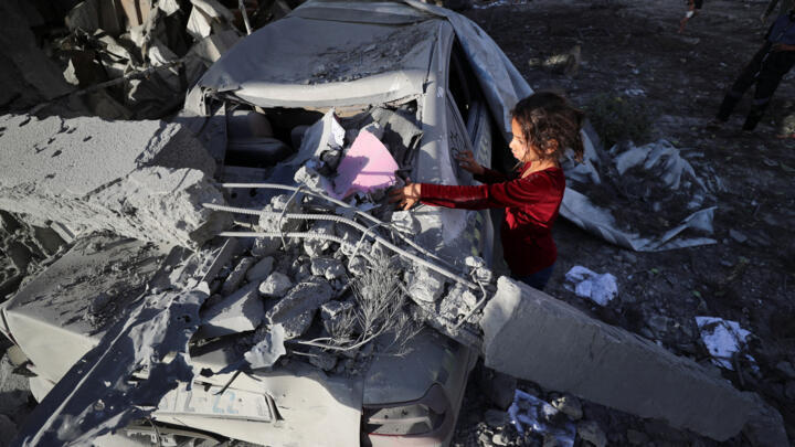 Una niña palestina garabatea en un coche dañado en el lugar de un ataque israelí contra una casa, en Jabalia, en el norte de la Franja de Gaza, 14 de mayo de 2025.