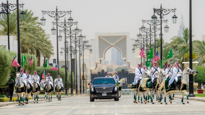 La voiture transportant le président américain Donald Trump est escortée par une garde d'honneur de soldats à cheval portant les drapeaux américain et saoudien, à Riyad, le 13 mai 2025.
